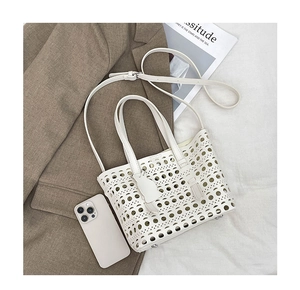 Detail of white hollow-out tote bag with cat charm and adjustable shoulder strap