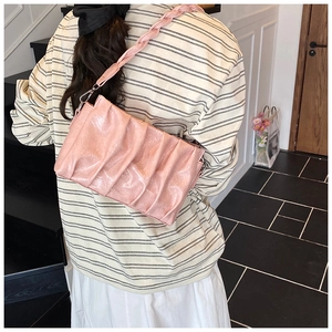 Détail macro de la texture plissée rose et de la bandoulière tressée du sac nuage chic