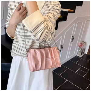 Detail of light pink cloud bag with vertical pleats and silver chain strap on model