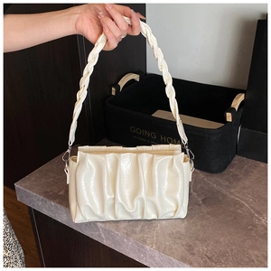 Détail du sac nuage beige en cuir brillant plissé avec bandoulière tissée et textures fines
