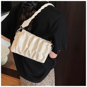 Detail of cream pleated cloud bag with braided handle and metallic silver buckle