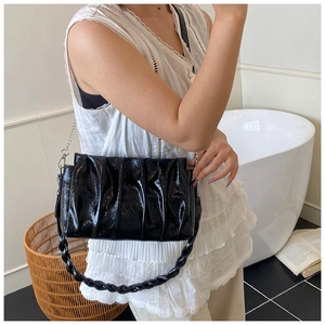 Close-up of black pleated cloud bag with silver chain and woven strap detail