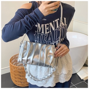 Silver metallic cloud bag with gathered pleats and thick chain strap on model