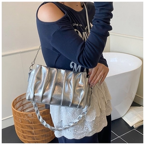 Detail of silver ruched cloud baguette bag with braided handle and chain strap on shoulder