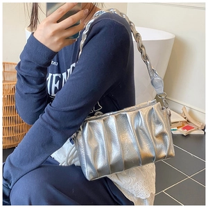 Détail d'un sac argenté métallisé plissé avec large bandoulière tissée dans un décor lifestyle