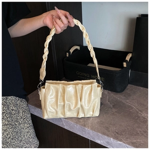 Gros plan sur un sac nuage plissé jaune crème avec cuir brillant et poignée tressée