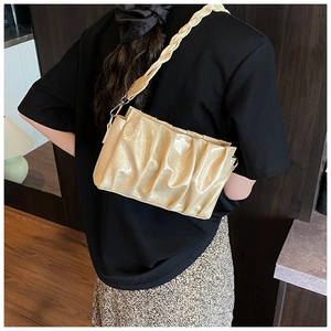 Détail d'un sac nuage plissé beige avec bandoulière tressée porté par un mannequin