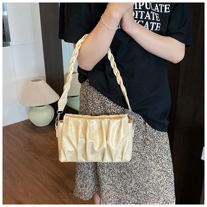 Détail du sac bandoulière plissé crème avec anse tressée porté par un mannequin