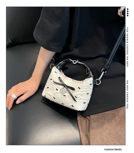 Détail du sac bandoulière crème avec tissu texturé et accents de ruban noir