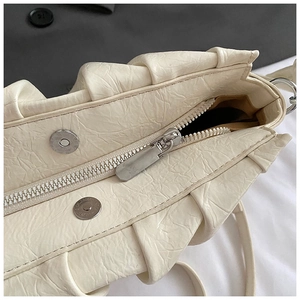 Gros plan sur la texture plissée et la fermeture éclair de ce sac nuage crème