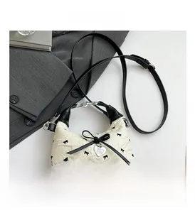 Détail d'un sac seau matelassé avec imprimé nœuds noirs et pendentif en cœur