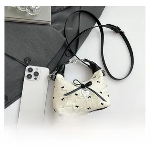 Détail du sac texturé floral avec nœud en ruban noir et breloque coeur