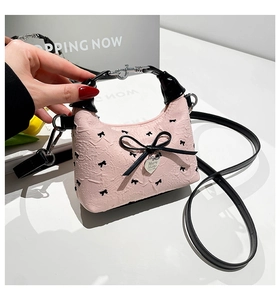 Sac bandoulière rose avec broderie nœud noir et détail de pendentif en cœur