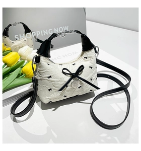 Détail d'un sac plissé blanc orné de nœuds noirs et d'un pendentif en cœur chic