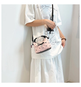 Détail du sac demi-lune rose avec motifs nœuds noirs et pendentif en cœur métal