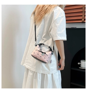 Détail du sac à bandoulière rose plissé avec nœuds noirs et pendentif en forme de cœur