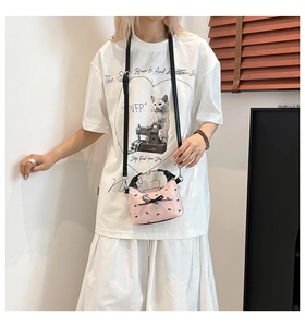 Vue détaillée du sac rose à nœuds avec breloque cœur et bandoulière noire réglable