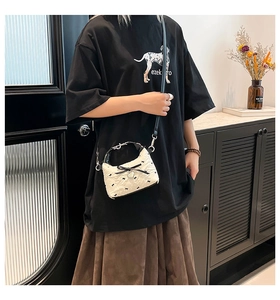 Détail d'un petit sac bandoulière matelassé avec nœud noir et pendentif cœur argenté