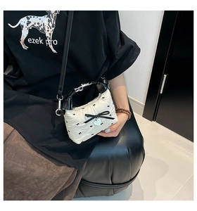 Détail du mini sac matelassé avec nœuds noirs et pendentif en forme de cœur argenté