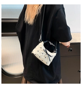 Sac à bandoulière matelassé blanc cassé avec motifs nœuds noirs et breloque cœur