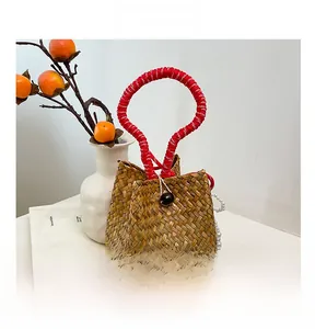Close-up of handmade straw tote with red woven handle and elegant pearl charm detail