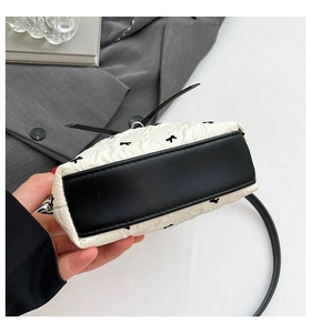 Détail du sac bandoulière matelassé blanc avec base en cuir noir et broderie d'étoiles
