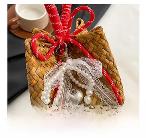 Detail of handmade straw bag with pearl charms, lace trim and silver heart pendant