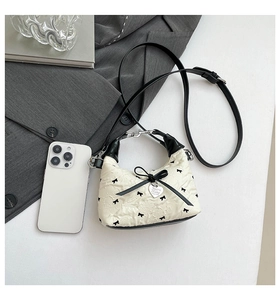 Détail du sac hobo en tissu floral avec nœuds noirs et pendentif en forme de cœur argenté