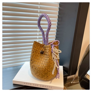 Detail of handmade woven straw bucket bag with purple rope handle and pearl lace decor