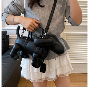 Schwarze Handtasche in Dackelform mit verstellbarem Riemen, getragen von einem Modell zu Hause