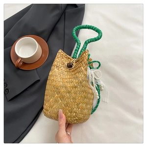 Detail of handmade straw tote with green handles, wooden bead and pearl lace accessory