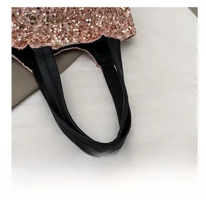 Détail du sac à paillettes roses montrant l'anse en cuir noir et les coutures soignées
