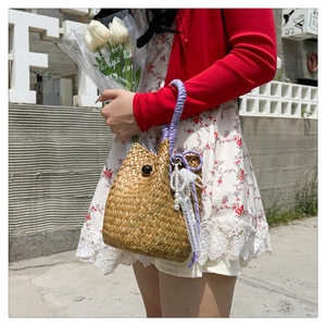 Detail of straw bucket bag featuring purple woven handles and lace pearl charms