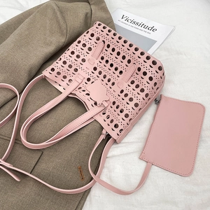 Pink hollow-out tote bag with matching inner pouch on stylish blazer and fabric backdrop