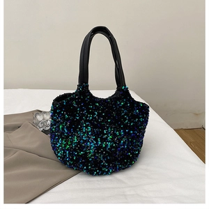 Détail de la texture des paillettes bleues et vertes et des anses en cuir noir sur le sac