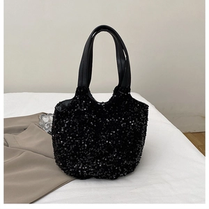 Détail de la texture scintillante en paillettes noires et des poignées en cuir du sac