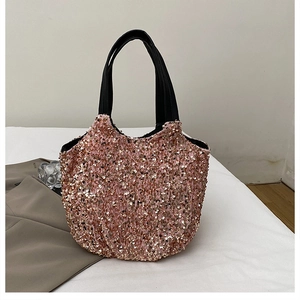 Détail d'un sac à paillettes rose et doré avec poignées en similicuir noir et broderies