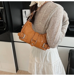Detail of glossy caramel leather shoulder bag with silver hardware and buckles