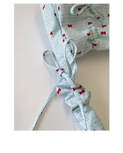 Détail du tissu seersucker bleu clair à nœuds rouges et design de bandoulière nouée
