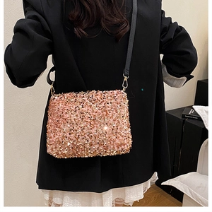 Gros plan du sac à bandoulière en sequins or rose avec sangle noire et attaches