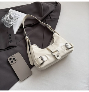 Detail shot of a cream underarm bag with silver buckles and smooth synthetic leather texture