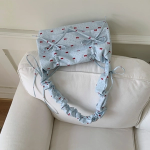 Detail of floral cloth bag with red bow print and elegant pleated fabric texture
