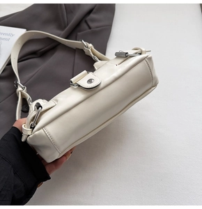 Detail of cream white faux leather shoulder bag with silver hardware and sleek texture