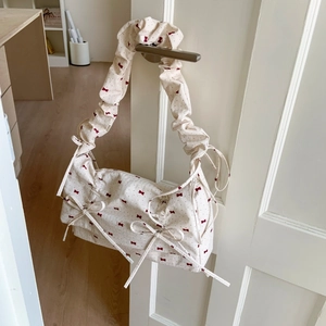 Detail of floral fabric bag with red bow prints and ruffled handle on door handle