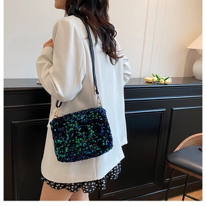 Détail du sac à bandoulière à paillettes vert et bleu sur un mannequin en blazer blanc