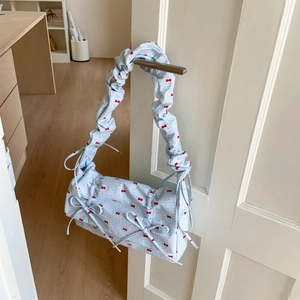 Detail of light blue floral fabric bag with red bow patterns and ruched cloud handle