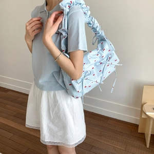 Close-up of light blue floral fabric bag with red bow print and ruffled shoulder strap