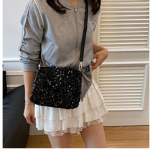 Détail du sac seau à paillettes noires avec crochets dorés et fine bandoulière en cuir