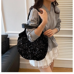 Détail d'un sac cabas à paillettes noires avec anse en cuir dans un décor intérieur chic