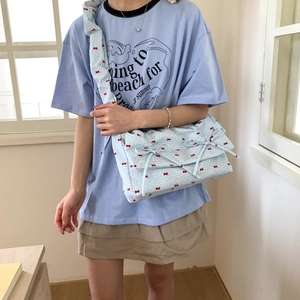 Floral print shoulder bag with bow accents and ruffled strap shown on model